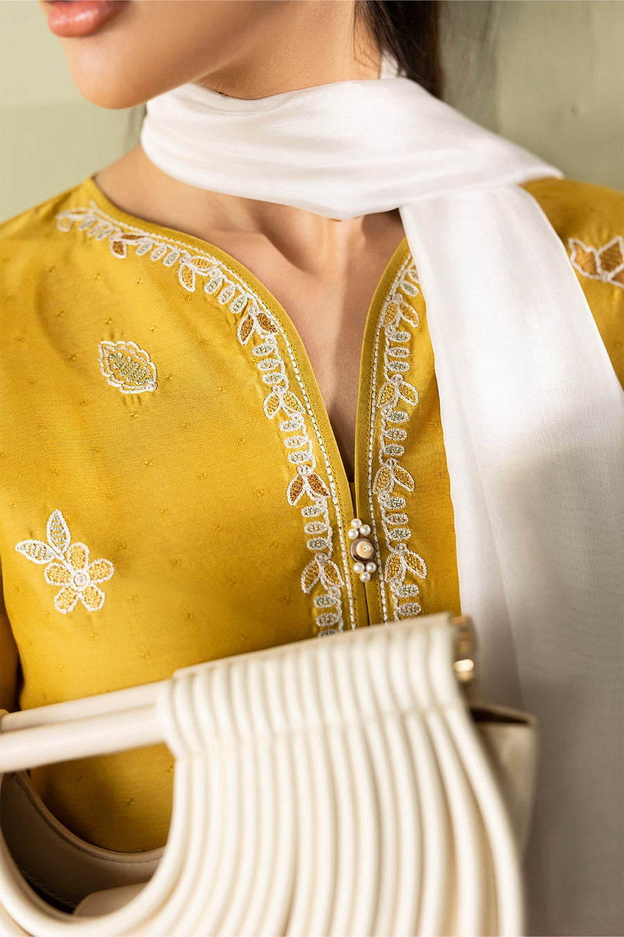 Close-up of shirt neckline featuring intricate white embroidery with pearl button detailing and a white dupatta draped over shoulder