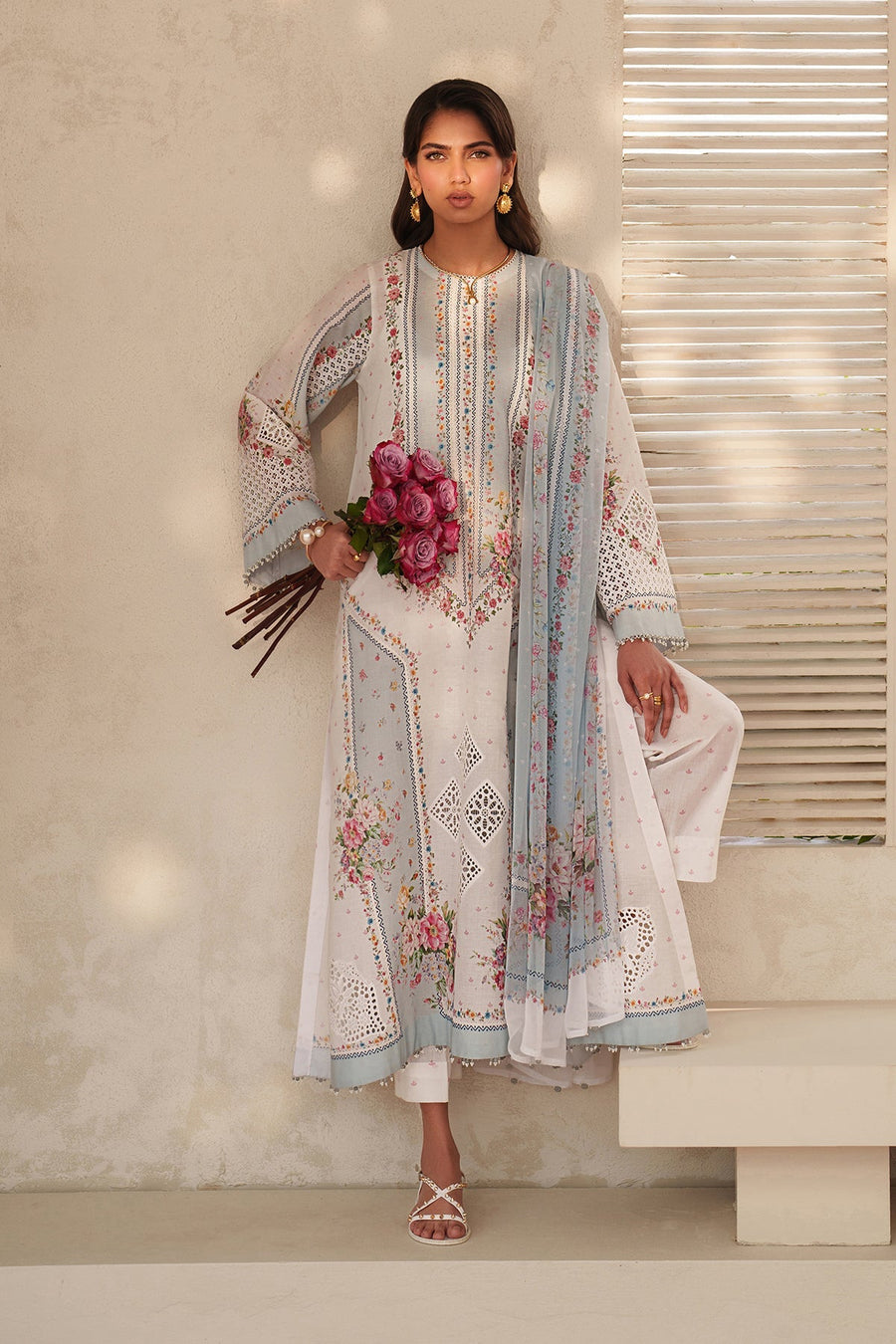 Woman seated wearing embroidered lawn suit, holding bouquet of pink roses, showing embroidery and cutwork details clearly