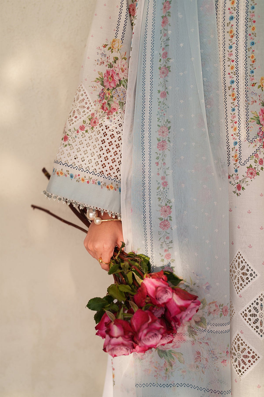Close-up of embroidered dupatta fabric with floral prints and fine pearl bead border held by model