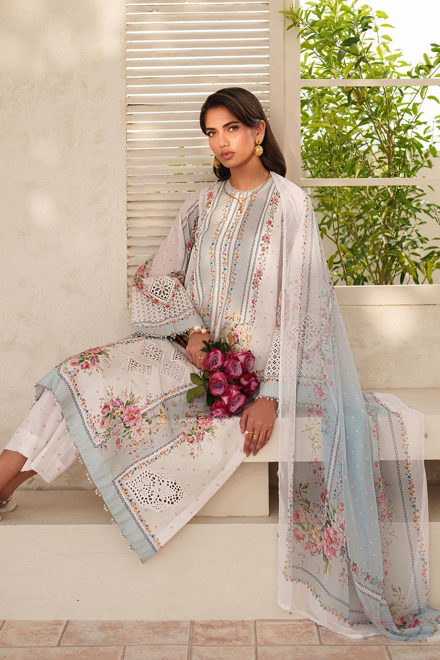 Side view of embroidered lawn suit with cutwork motifs, pearl trims, and digital prints, paired with white studded sandals