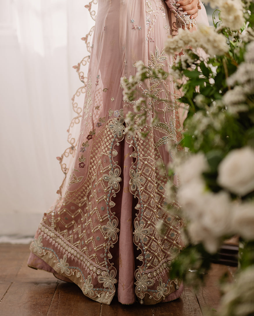 Detailed close-up of dress lower hem showing ornate floral embroidery, sequin details, and layered fabric design