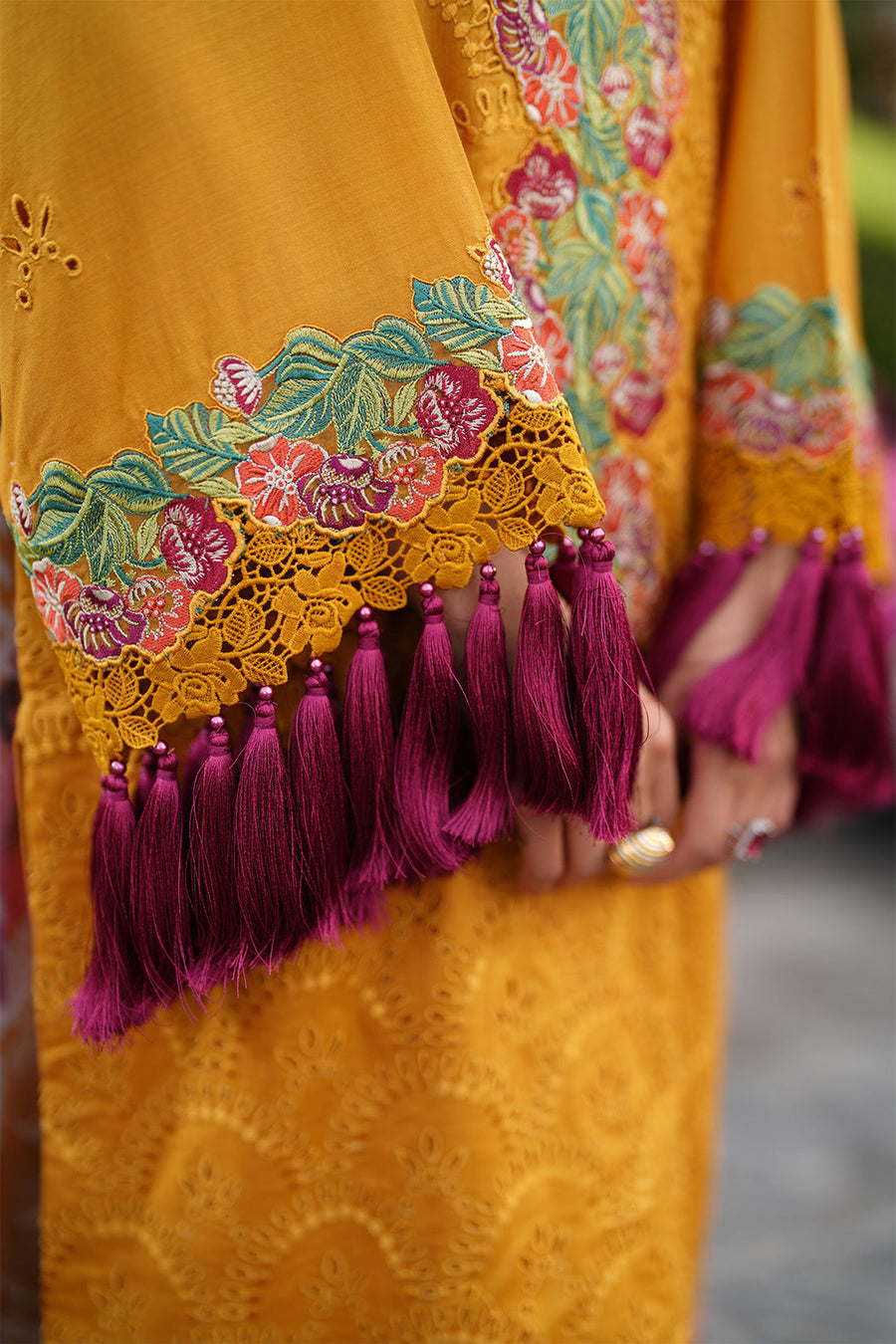 Close-up of bottom hem embroidery and tassels on yellow lawn trousers and shirt