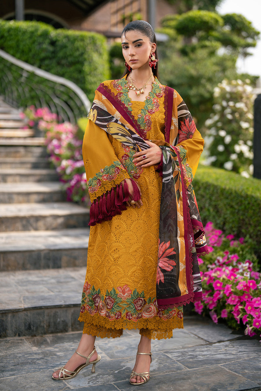 Woman holding maroon tassel-edged printed dupatta showcasing embroidery and accessories close-up