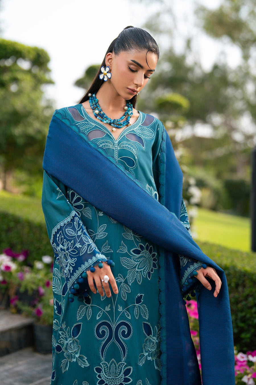 Close side angle displaying embroidered floral motifs and pompom trim on sleeves of lawn shirt