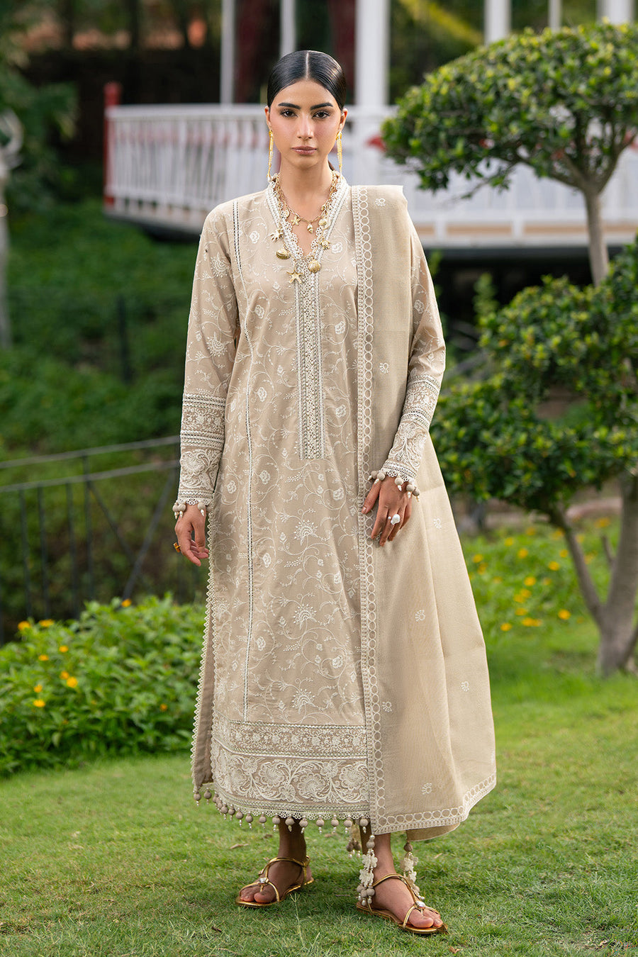 Front view of elegant beige embroidered lawn suit with detailed embroidery and tassel hem