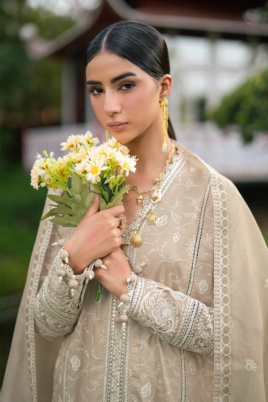 Side view of model draped in embroidered dupatta over lawn suit and gold sandals