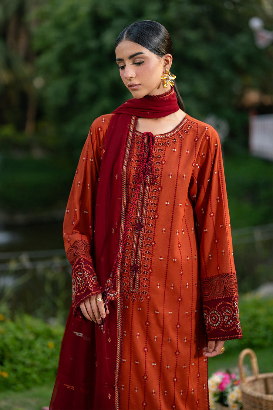 Close up of neckline and sleeves showing intricate embroidery in rust orange and maroon