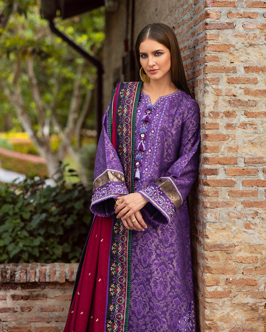 Close-up of woman in purple jacquard outfit showing delicate silk embroidery on the neckline and sleeves, paired with a red and floral embroidered shawl draped over her shoulder.