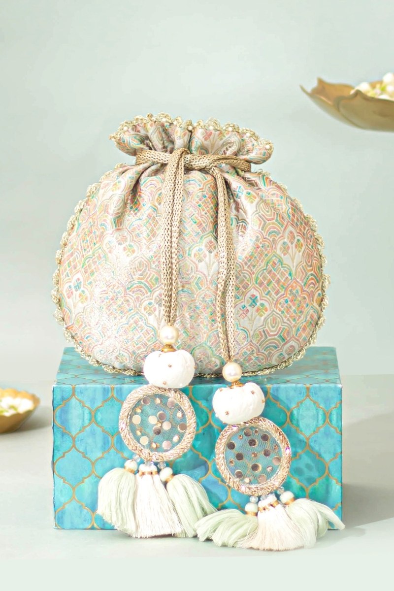 Pastel multicolor Banarasi potli bag with drawstring closure, tassels, and decorative beads displayed on a turquoise patterned box
