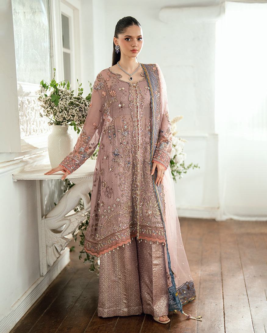 Front view of a woman wearing an embellished pastel mauve chiffon kameez with matching brocade wide-legged pants and embroidered dupatta standing indoors