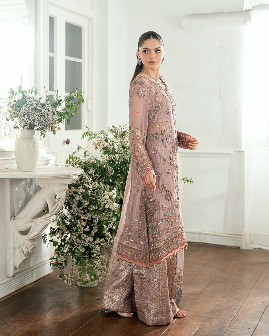 Side view of the woman showing the detailed embroidery and silhouette of the chiffon kameez paired with brocade trousers