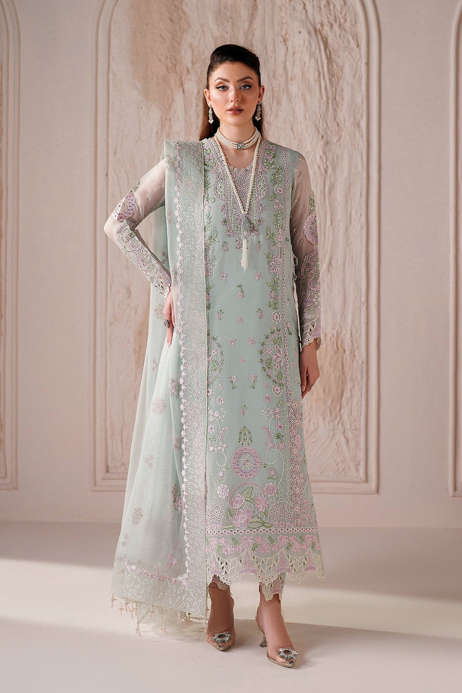 Front view of woman wearing pastel green embroidered chiffon suit with floral designs and sheer full sleeves