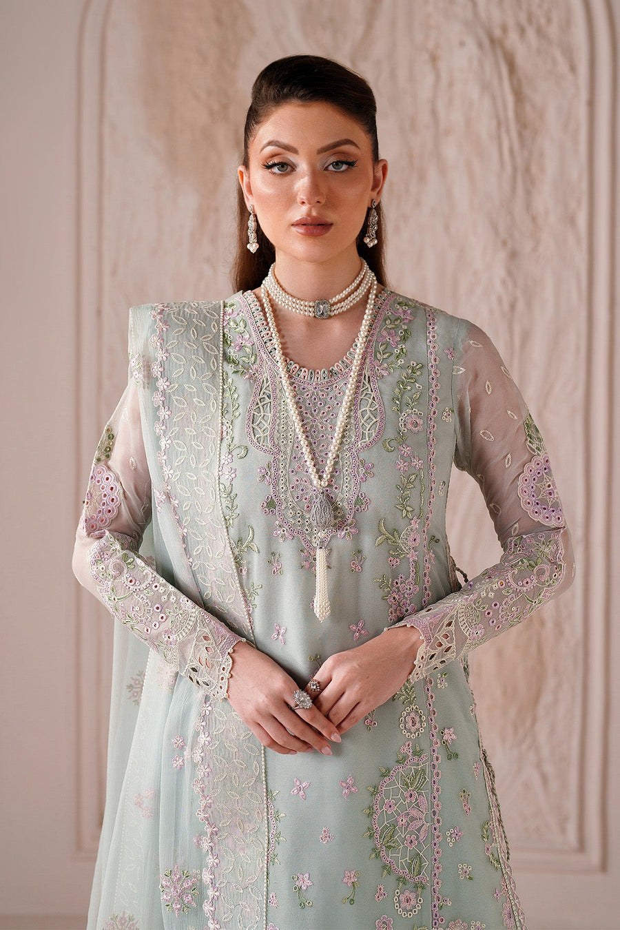 Close-up of embroidered floral neckline and sheer sleeves on pastel green suit