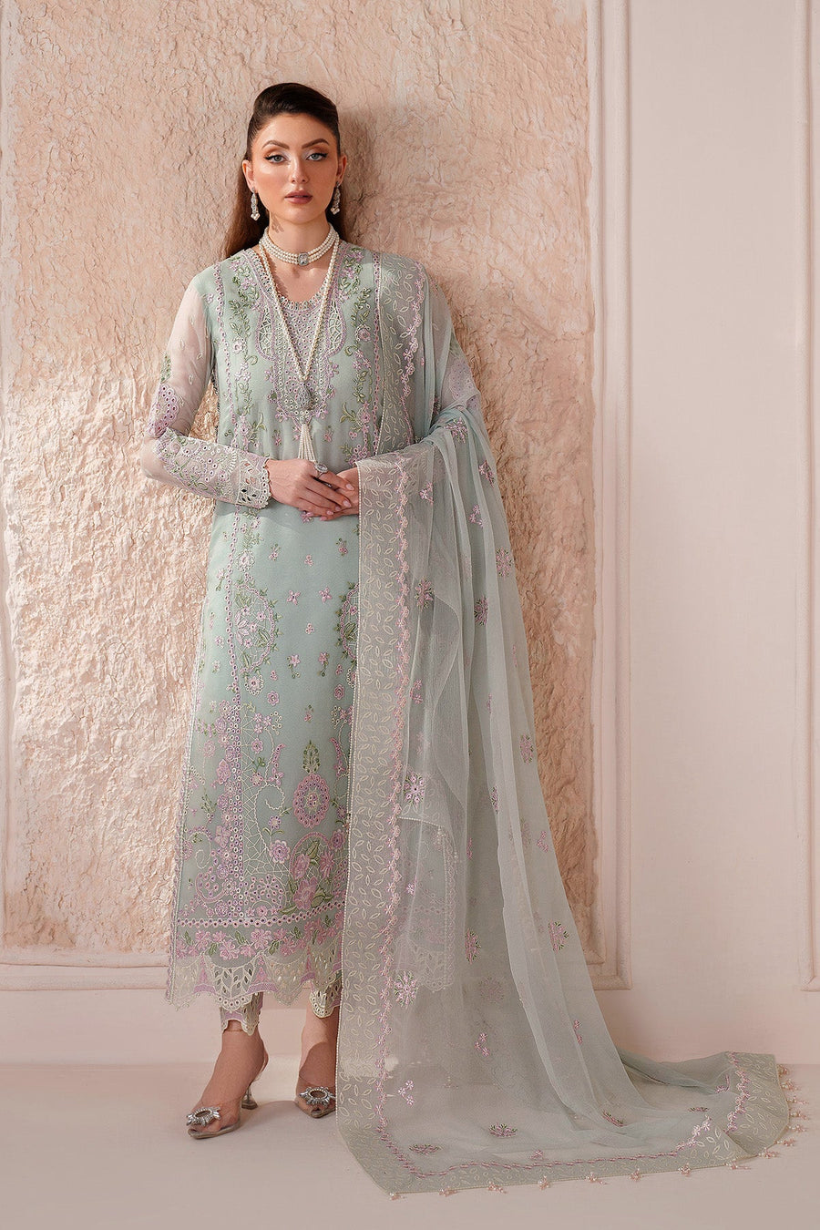 Detailed image of suit's embroidery with woman posing in matching jewelry