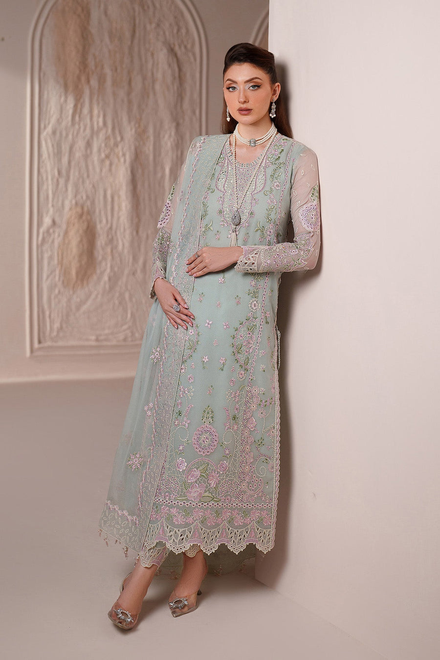 Stylish pose of woman in embroidered chiffon suit paired with pearl necklace and earrings