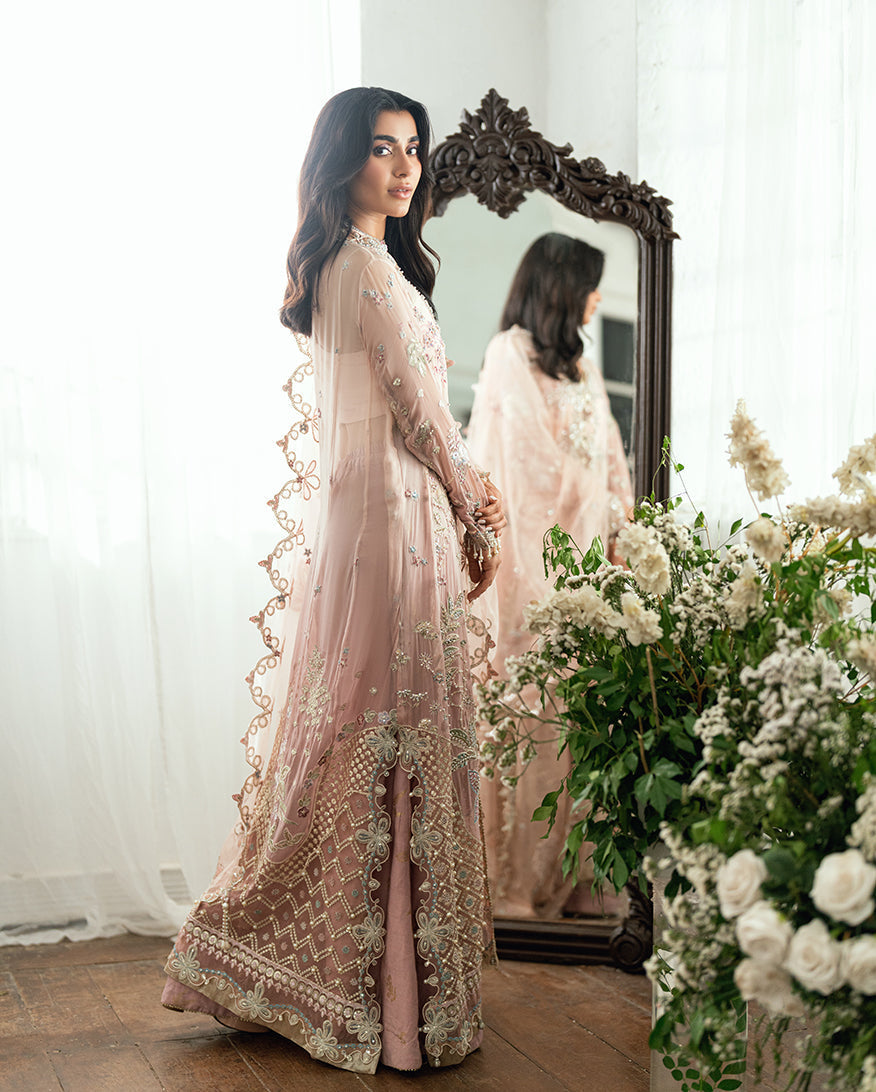 Side view of woman in embroidered chiffon dress showcasing intricate floral patterns and delicate sheer sleeves