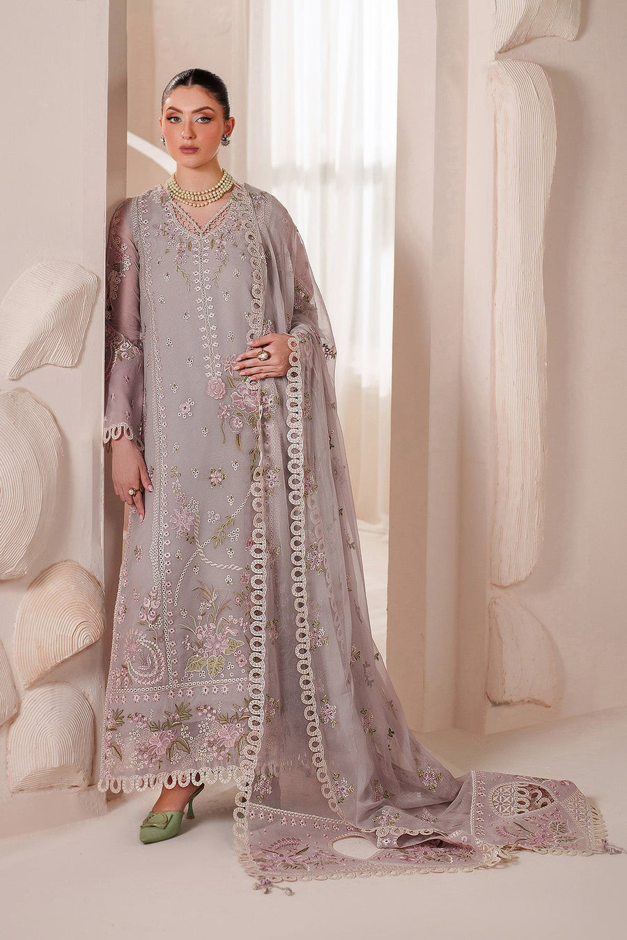 Close-up of model with pearl necklace showcasing embroidery and cutwork on suit