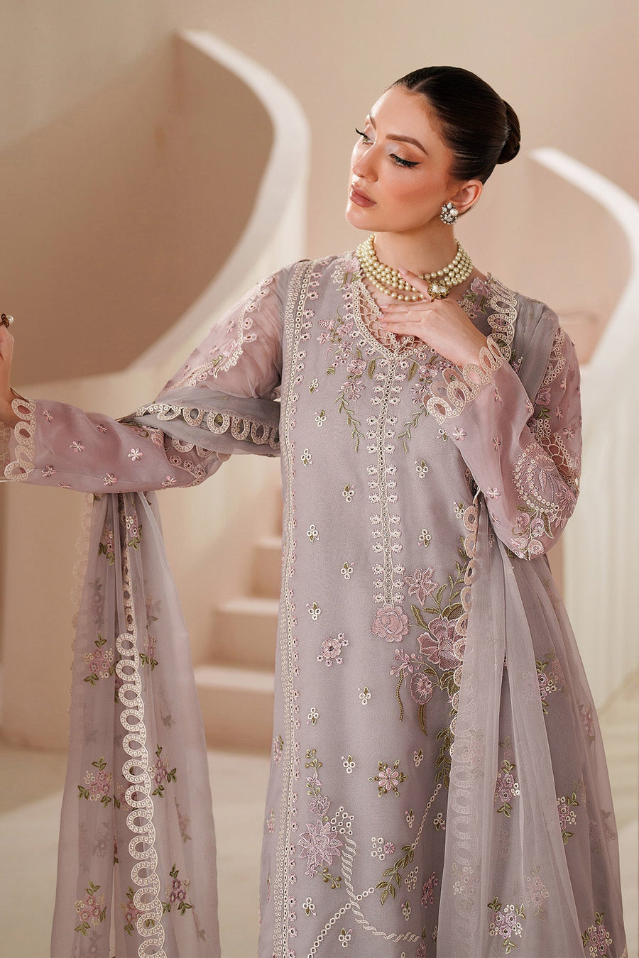 Model leaning on wall wearing lavender chiffon embroidered formal suit with accessory details