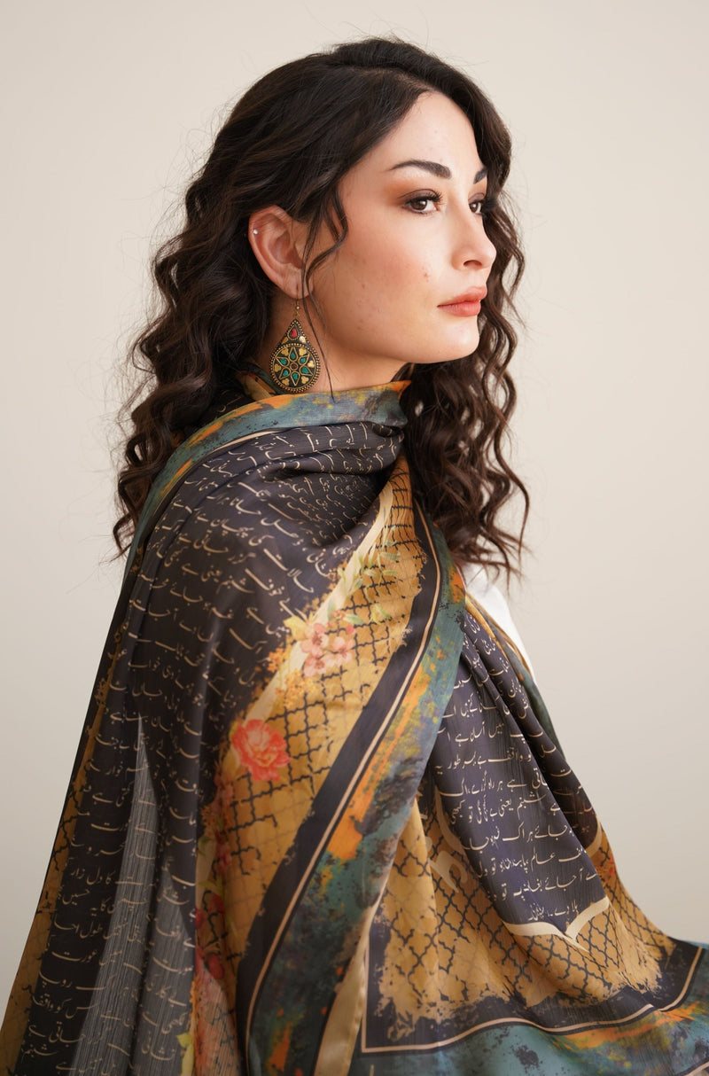 Profile of woman wearing a luxurious black and gold silk scarf with Urdu calligraphy and floral patterns