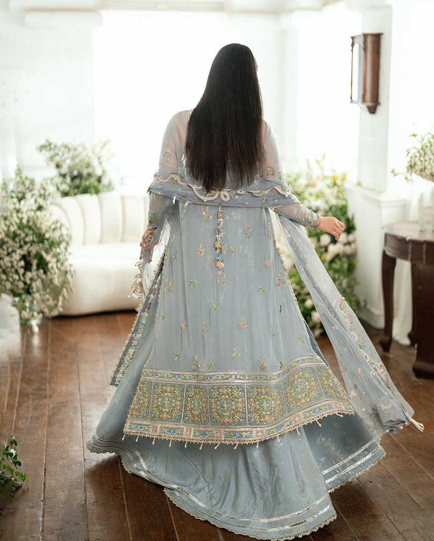 Rear view of embroidered chiffon dress highlighting the intricate floral motifs and scalloped hem detailing with flowing fabric