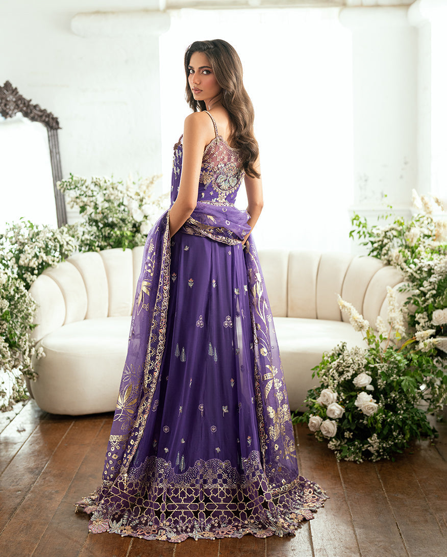 Back view of woman in purple chiffon gown showing intricate embroidery and sheer organza back panel, holding the embroidered dupatta