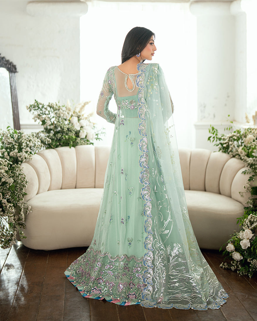 Back view of woman in formal pastel mint green chiffon dress featuring keyhole back and embroidery