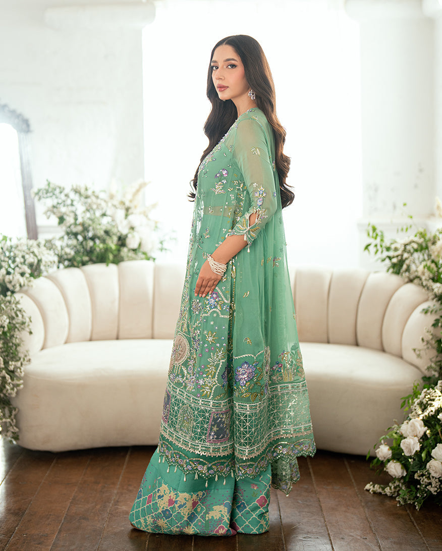 Side profile of woman in soft green chiffon embroidered suit showcasing delicate sleeves and printed wide trousers