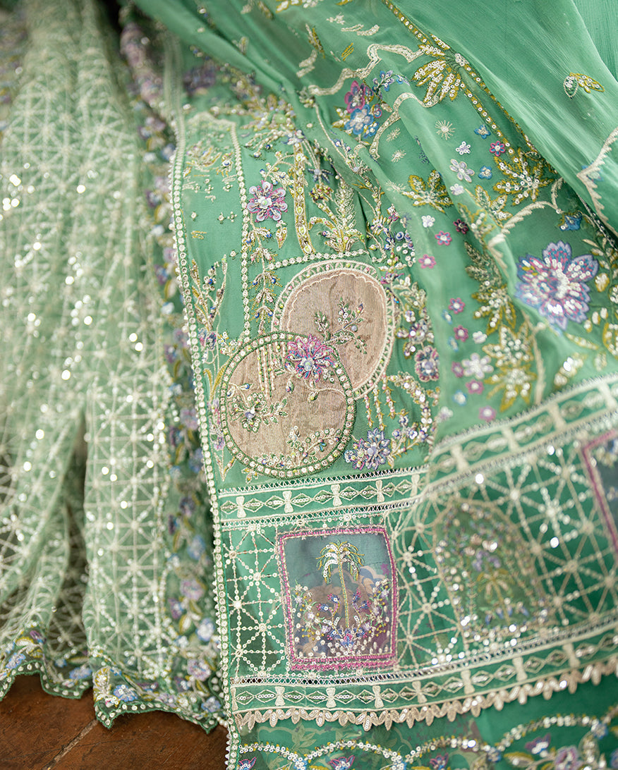 Green embroidered formal outfit displayed draping the chiffon dupatta over the arm highlighting the intricate hand-embellishments