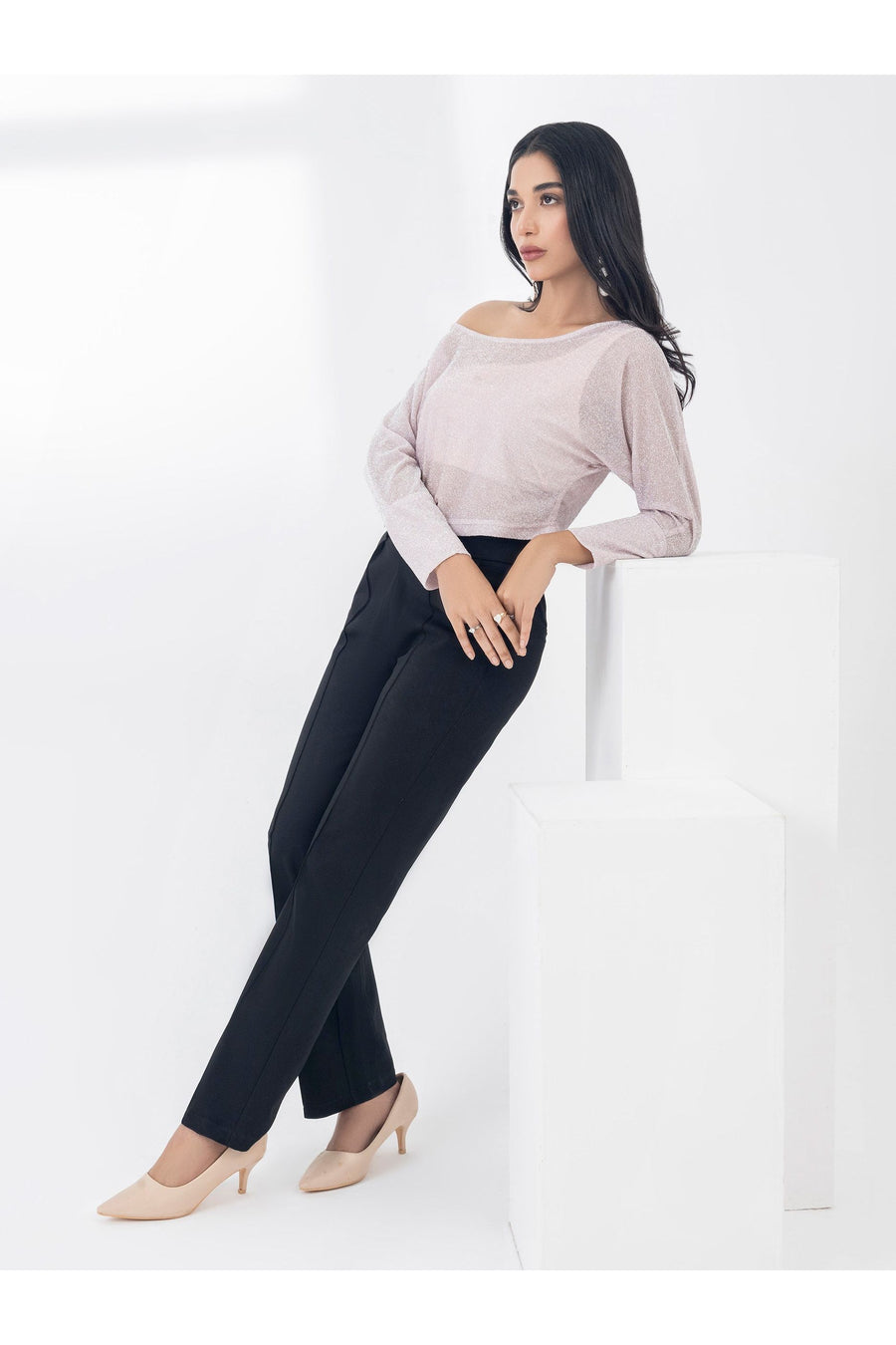 Model in a dyed jersey top and black trousers, leaning back on a white block