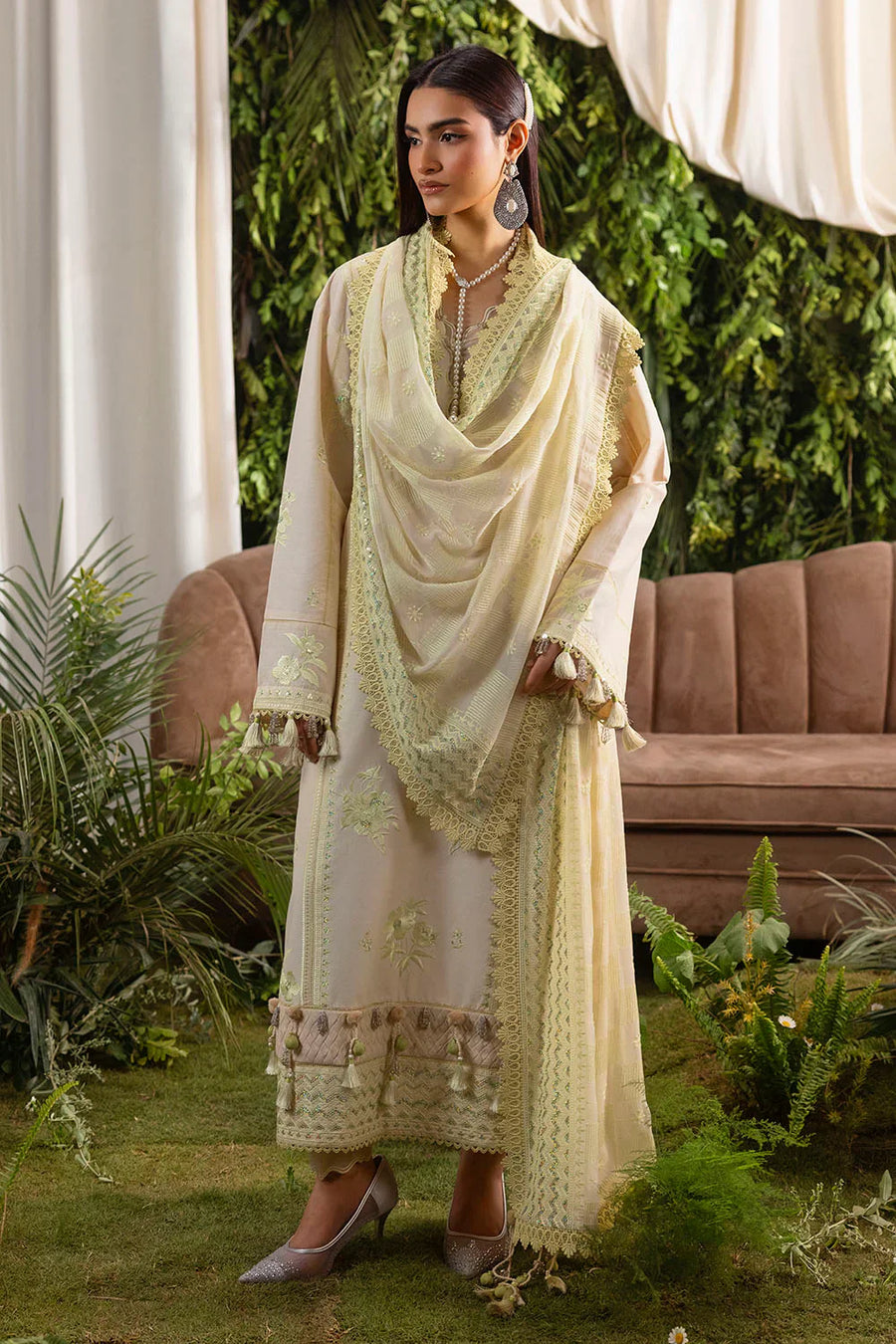 Side rear angle shot showing back embroidery and lace hemline on pastel cream lawn suit with tassel embellishments