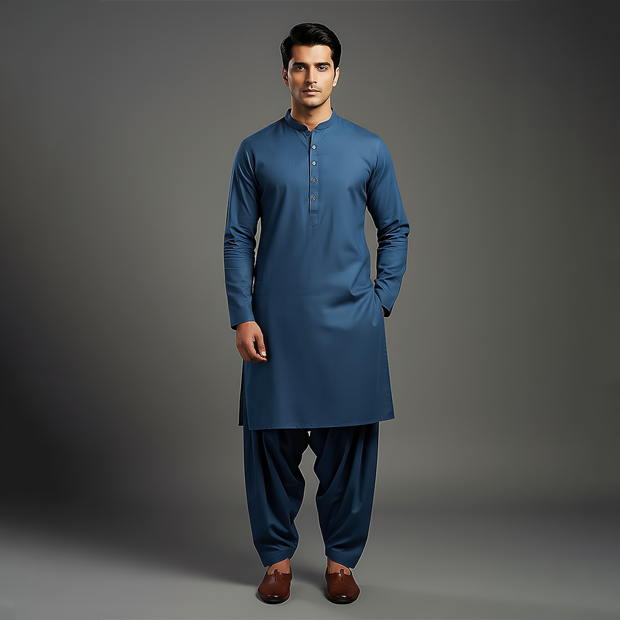 Front view of a man wearing a deep blue slim fit kurta-shalwar set with a mandarin collar and brown loafers on a plain gray background