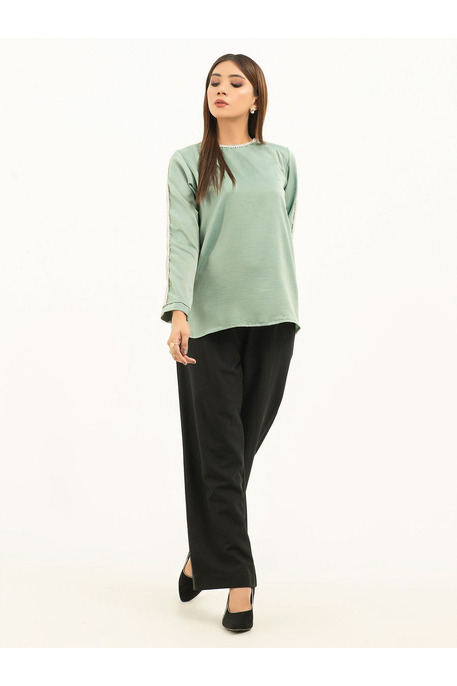 Model wearing a light green embellished viscose top with black pants, front view