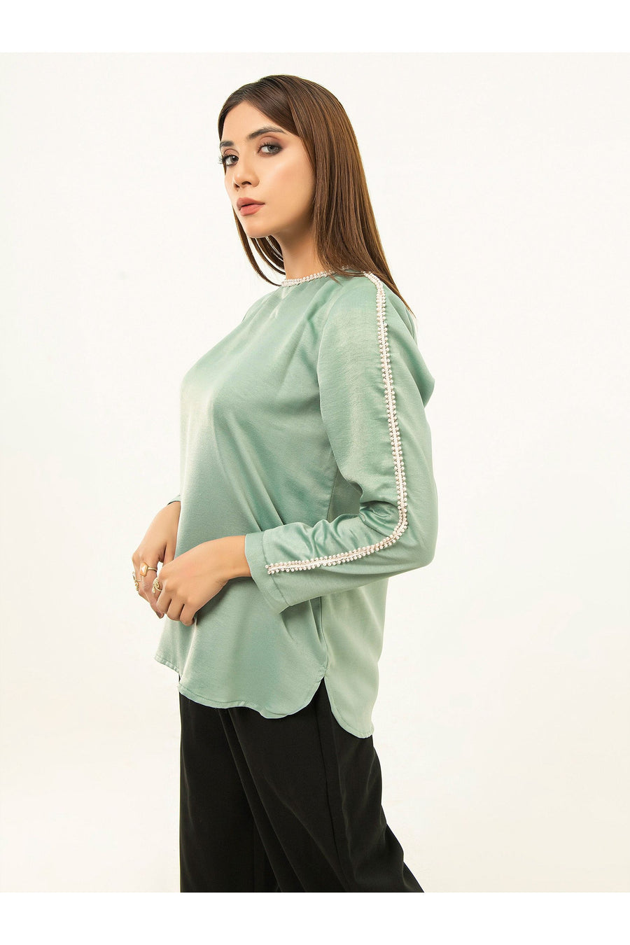 Close-up side view of embellished pearl lace detailing on sleeve and neckline of green viscose top