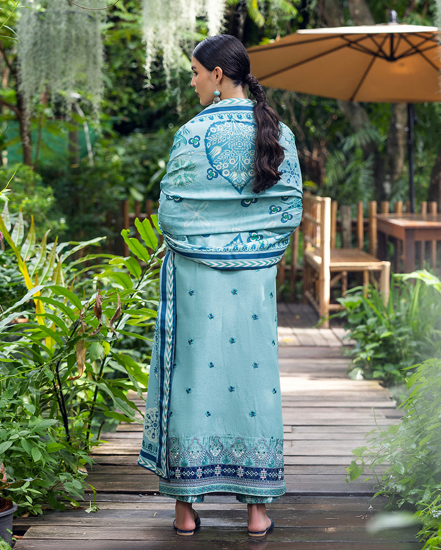 Back view of the woman wrapped in the aqua blue printed dupatta, highlighting the detailed embroidery on the back of the karandi shirt and trousers.