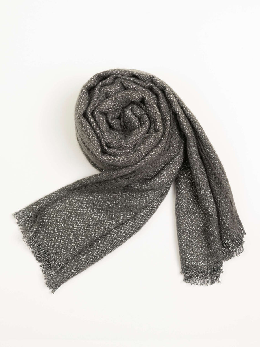 Slate grey wool shawl rolled neatly with visible herringbone pattern and fringed edges