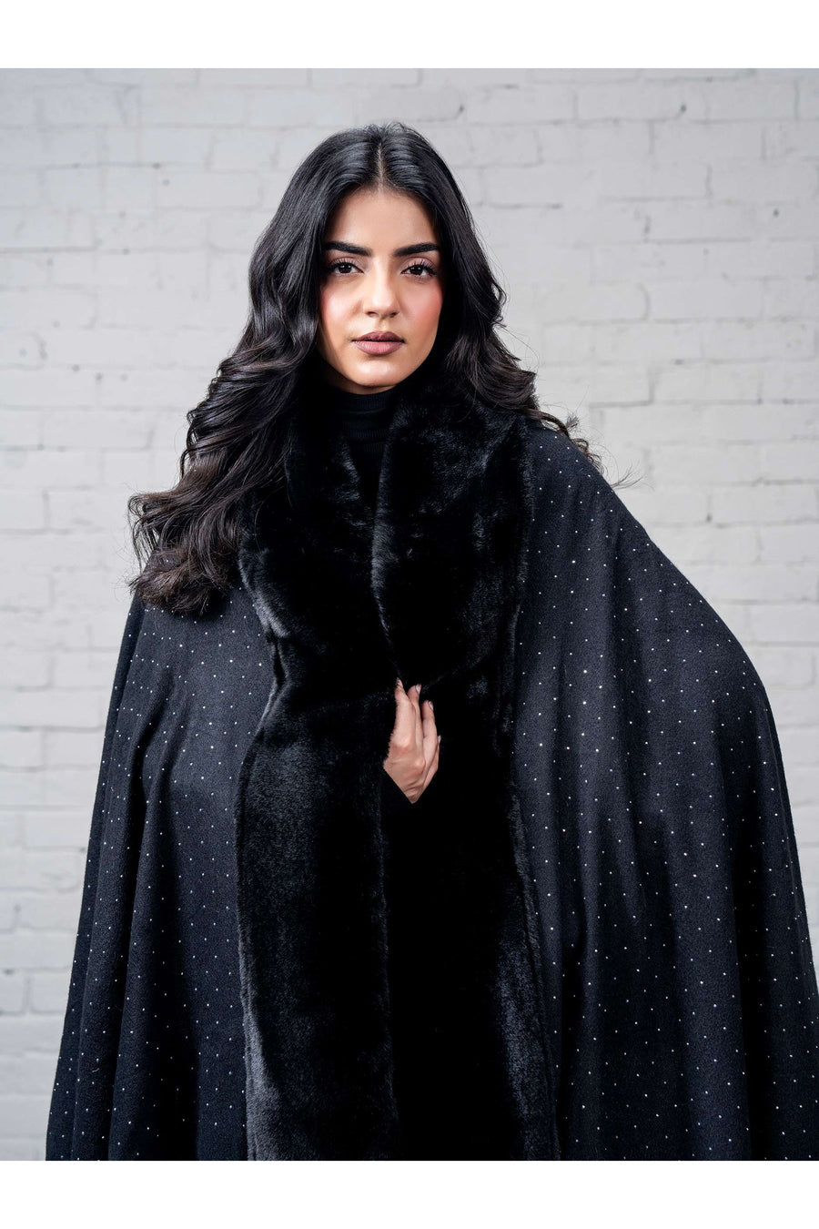 Detailed close-up of the cape's plush faux fur trim and fine wool fabric with rhinestone accents on the cape body
