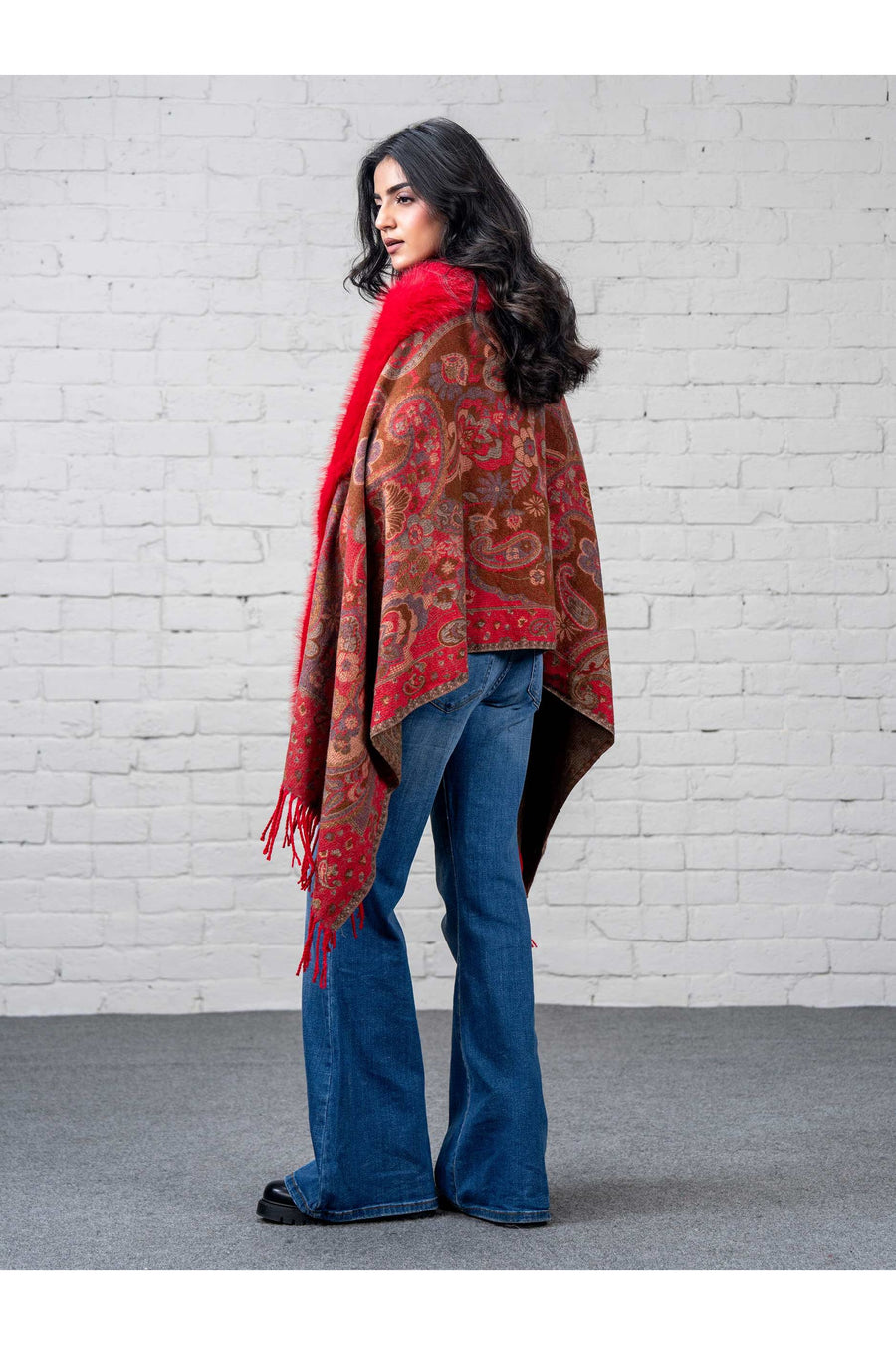 Close-up image of a woman wearing the red faux fur trimmed cape showing detailed floral paisley patterns and soft texture of the fabric, with the cape draped over one shoulder.