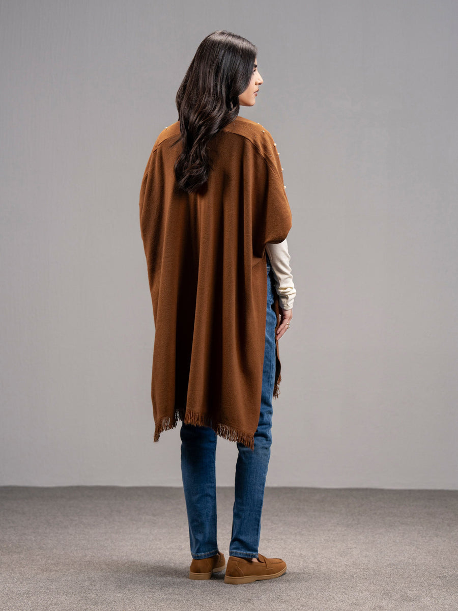 Back view of the woman wearing the rust wool blend cape showing the smooth fabric and fringed hemline.