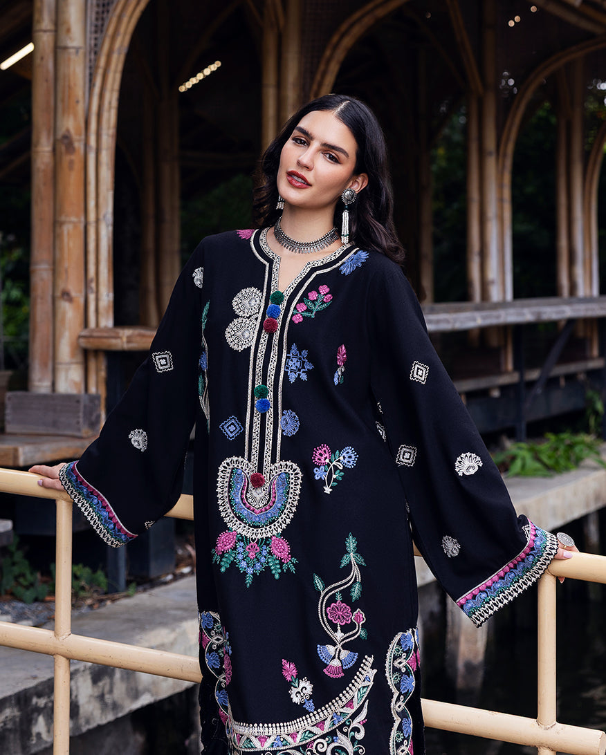 Close-up front view of black Karandi shirt embroidered with multicolored floral designs and decorative tassels at the neckline