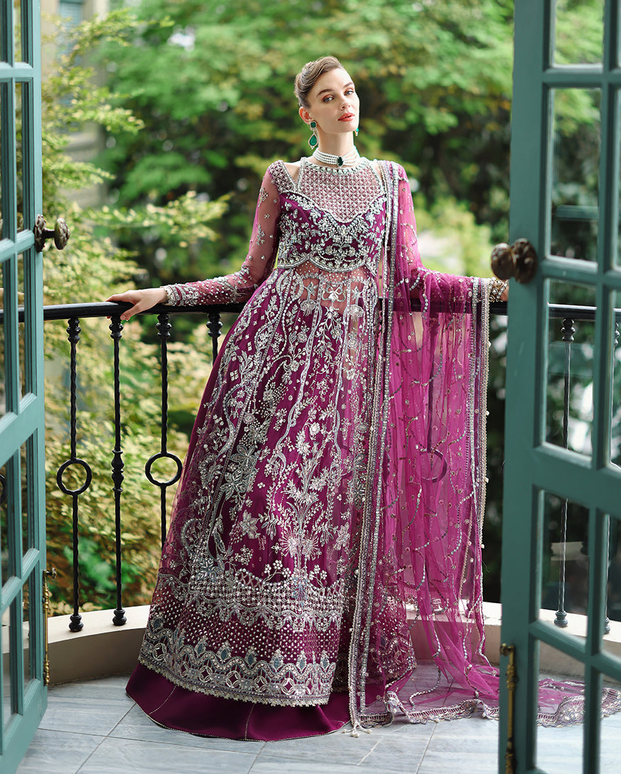Full-length view of woman posing gracefully in embroidered magenta wedding dress with matching decorated dupatta on balcony