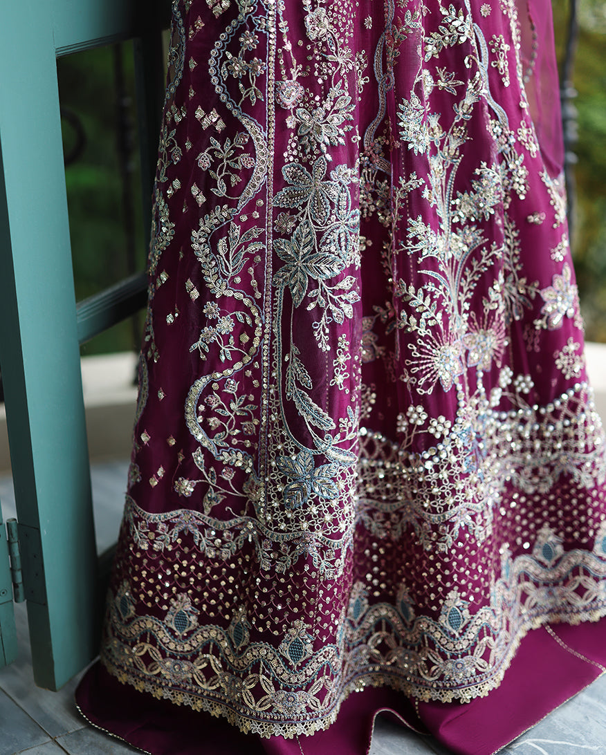 Close-up of the ornate floral silver embroidery and sequin work on the flare hem of the deep magenta dress