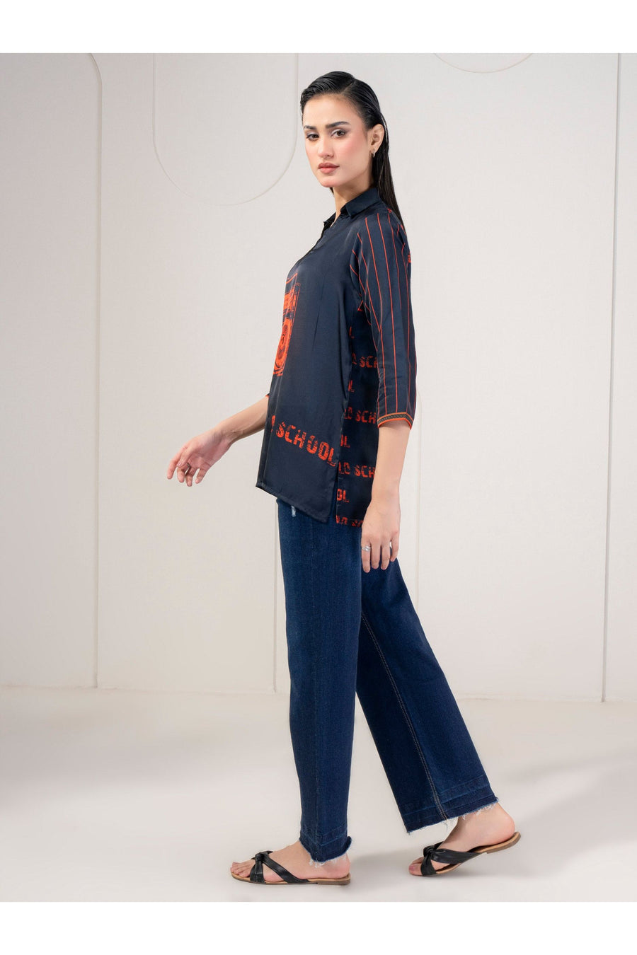 Profile view of model in navy silk printed top with striped sleeves and blue jeans.