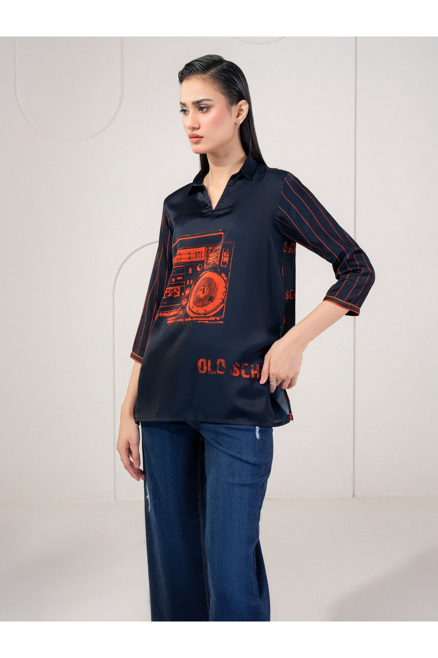 Side view of woman in navy silk top with orange print and pinstriped sleeves.