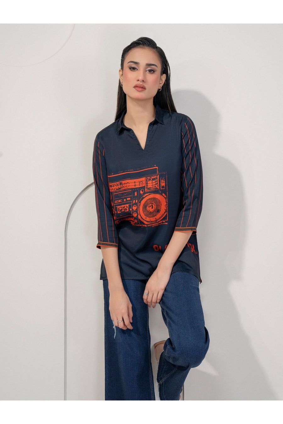 Front-facing view of woman wearing navy printed silk top and blue jeans.
