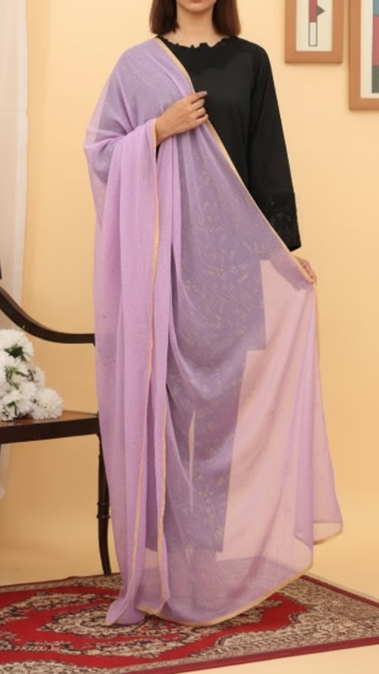 Woman draped in a lilac chiffon dupatta with golden border, paired with a black outfit, standing indoors.