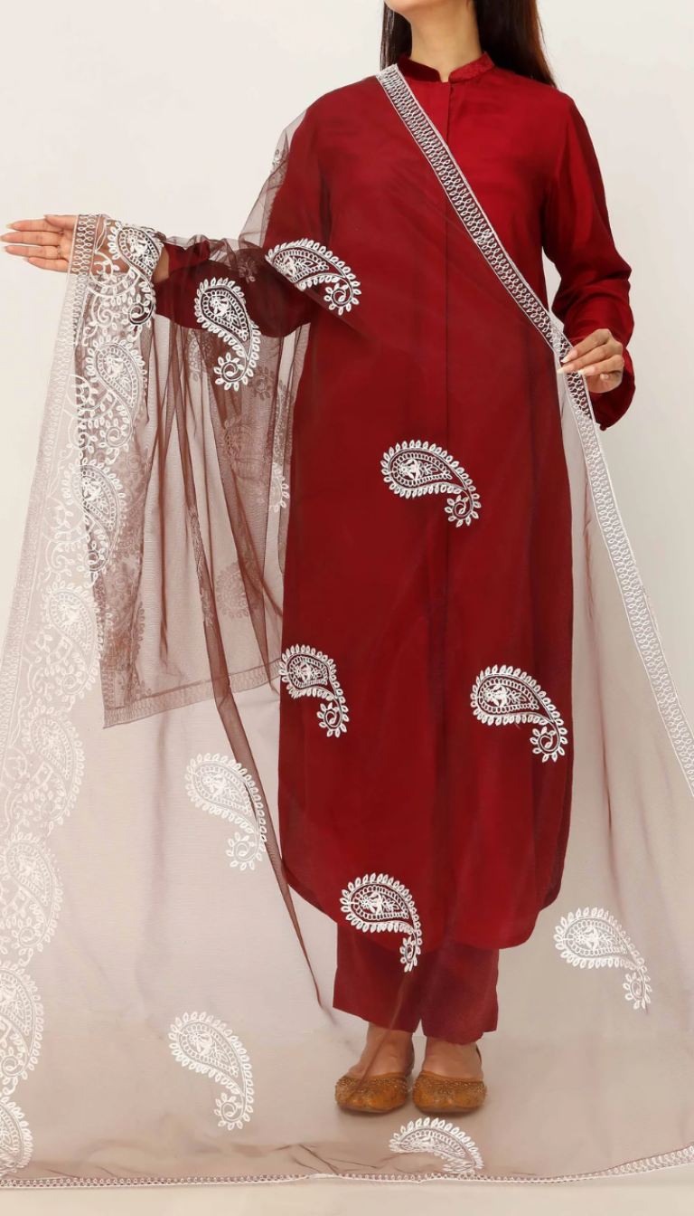 Woman showcasing a sheer brown cotton dupatta decorated with white embroidered paisley patterns, draped over a maroon traditional outfit.