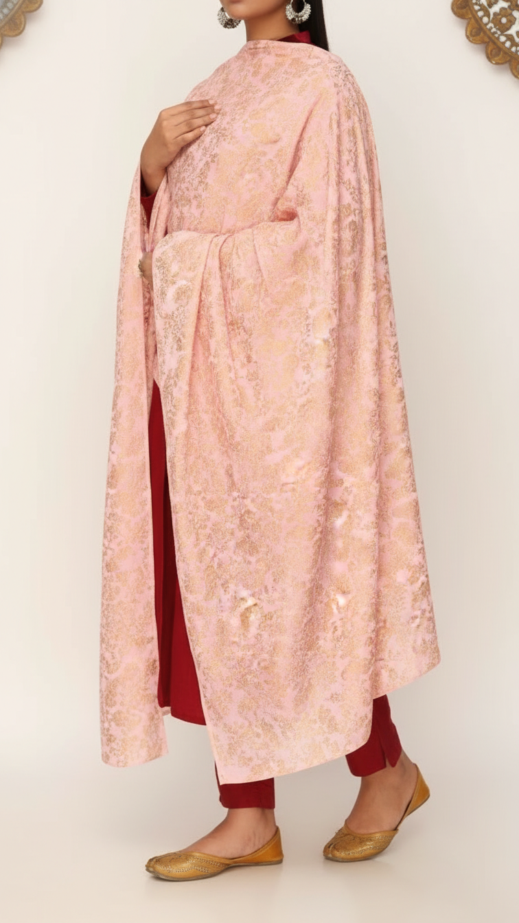 Woman wearing a pink cotton silk dupatta with intricate gold embroidery draped over a deep red outfit and golden traditional shoes
