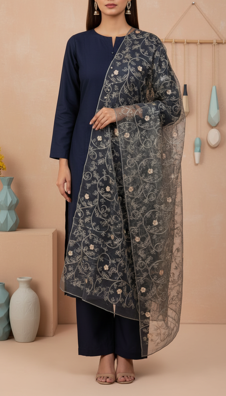Woman wearing a black embroidered net dupatta draped elegantly over a navy blue outfit, showcasing delicate floral embroidery on sheer fabric.