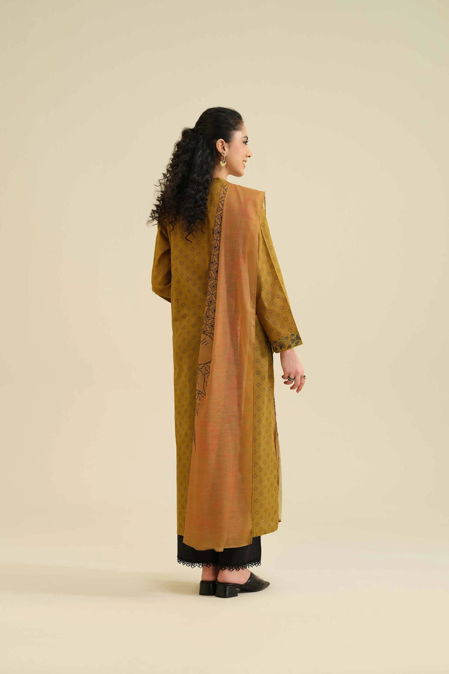 Model showcasing back view of mustard kurta with black trousers and dupatta draped