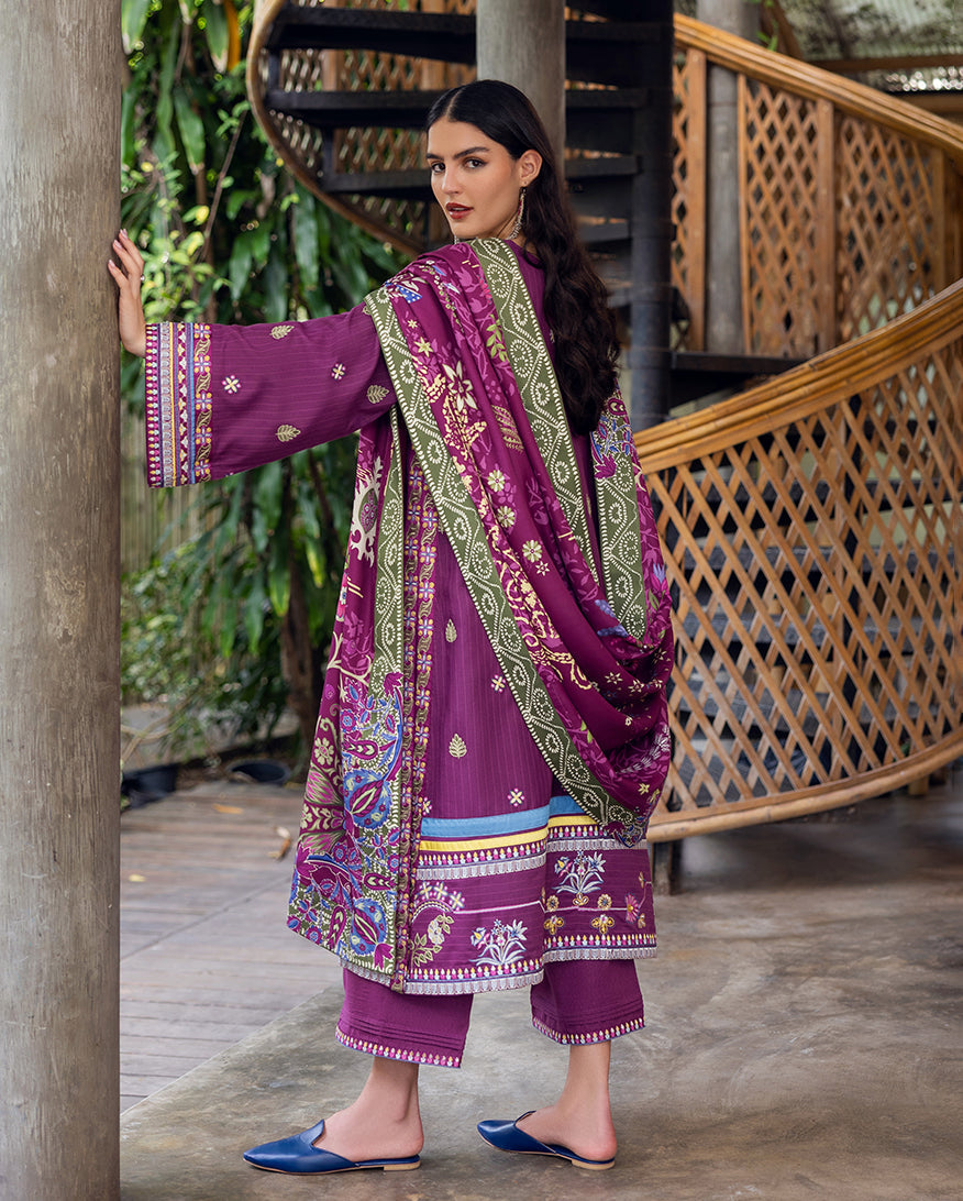 Rear view of model wearing embroidery detailed plum purple Karandi suit with floral printed shawl draped over shoulder.
